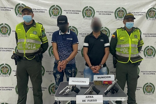 2 personas capturadas-policías custodiando-armas de fuego incautadas