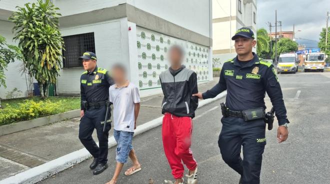 Dos policías conducen a dos capturados por el delito de hurto.