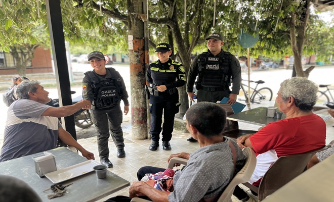 Tres funcionarios de la Polic&iacute;a Nacional, uno de ellos saludando a uno de los tres ciudadanos que reciben informaci&oacute;n sobre la prevenci&oacute;n de la extorsi&oacute;n y el secuestro