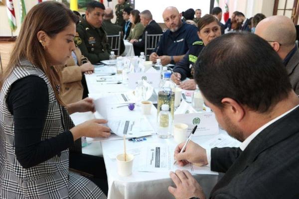Personas reunidas en mesa de trabajo, diligenciando formato con cuestionario, como insumo para los estándares del comandante de estación