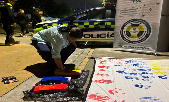 Una mujer de rodillas pintándose las manos de amarillo 