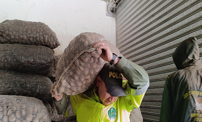 Policía cargando bulto de papas
