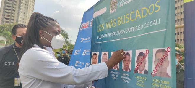 Cartel de los mas buscados en Cali-ciudadana observándolo 