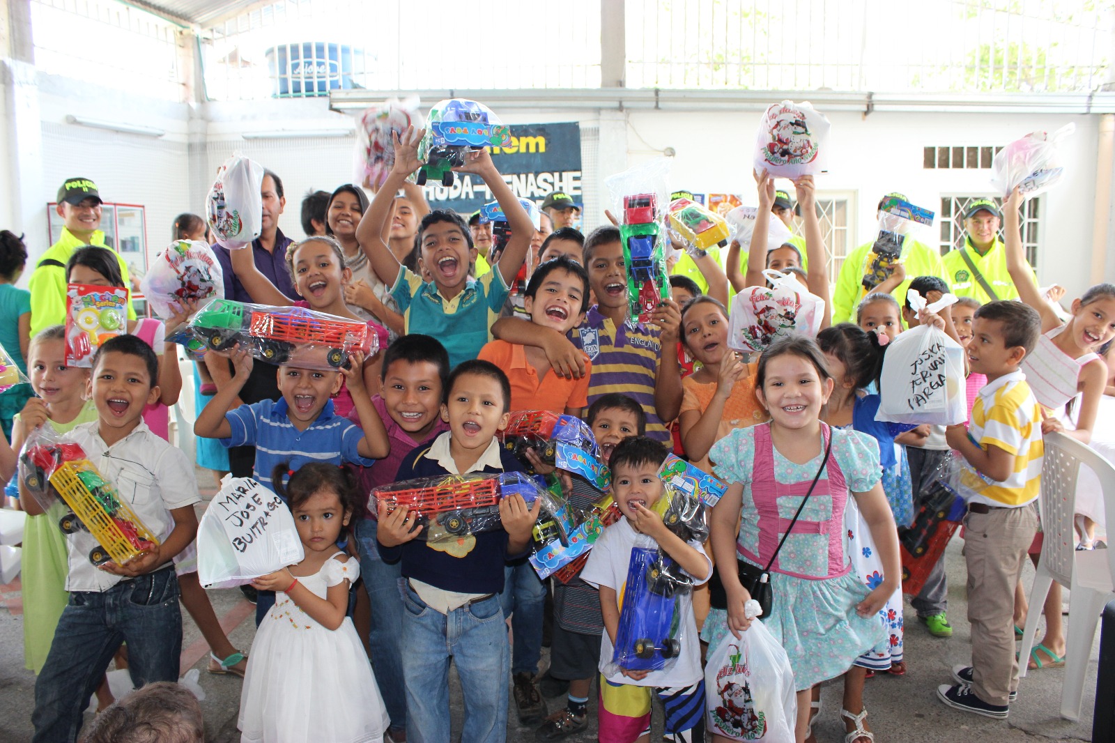 Niños y niñas rodeados de policías sonrien con regalos en sus manos