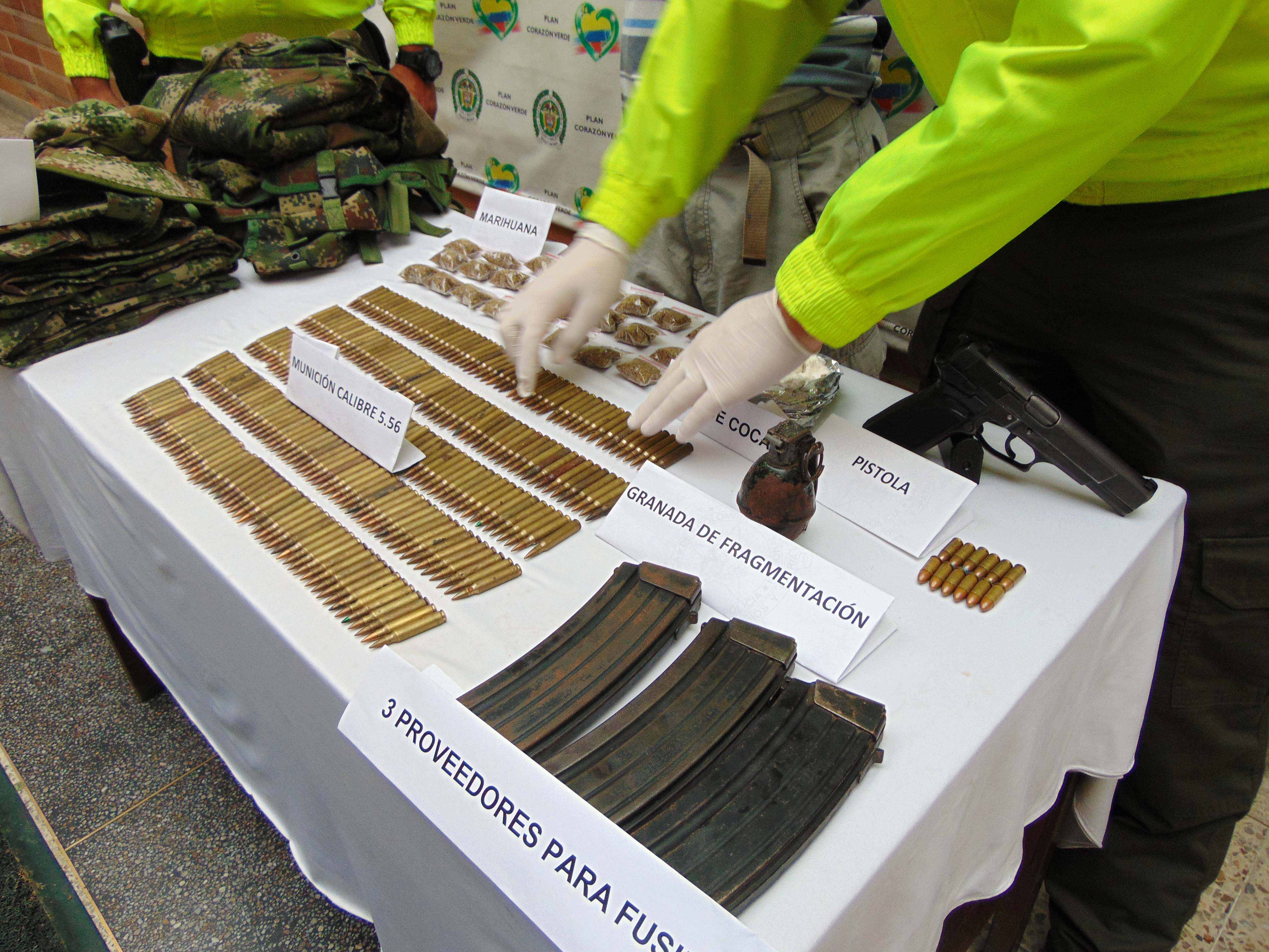 Hombre capturado con arma, granada, munición y droga es custodiado por dos policías de la Sijin en Medellín