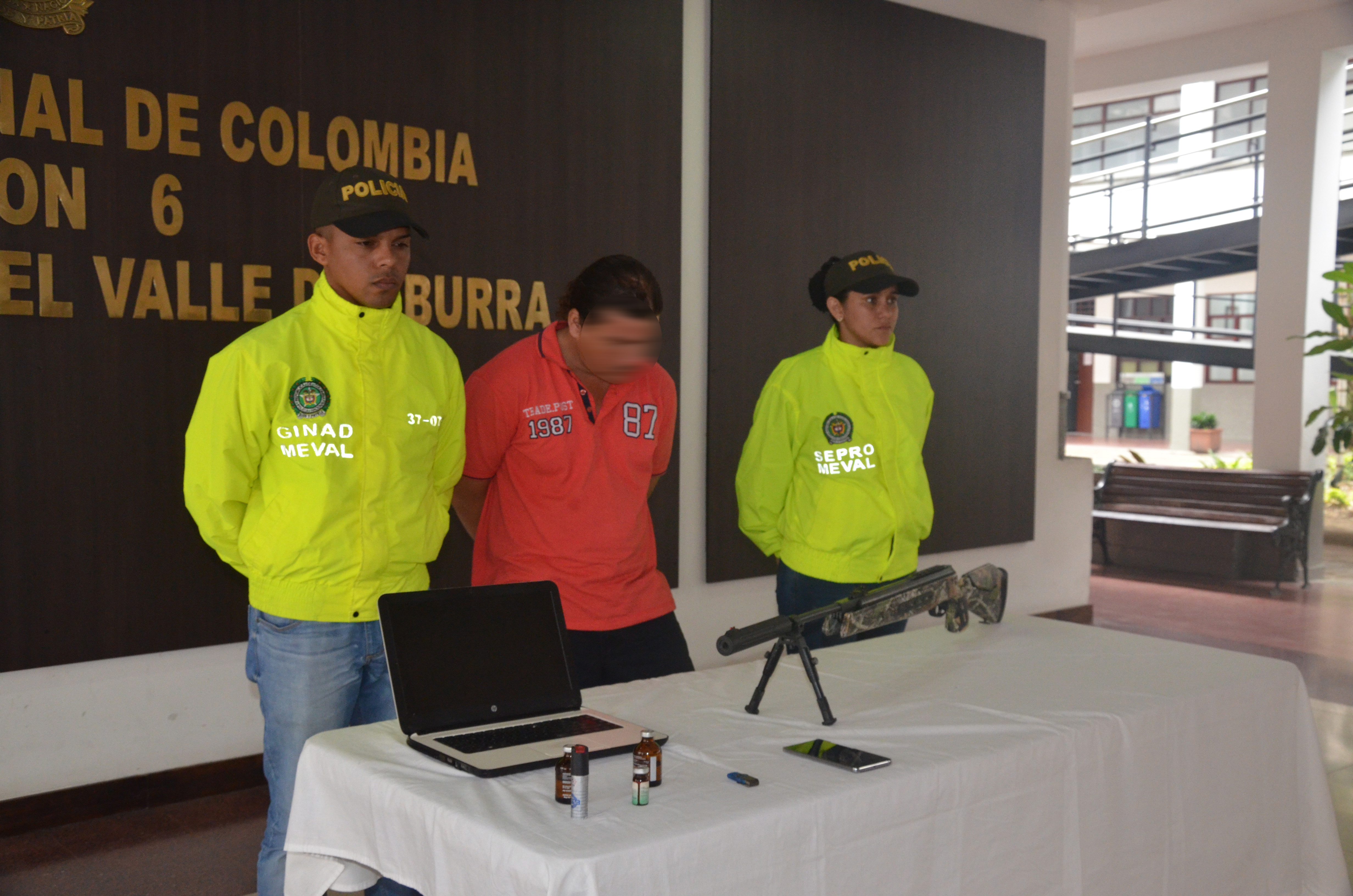 Hombre capturado junto con elementos incautados es custodiado por dos policías judiciales