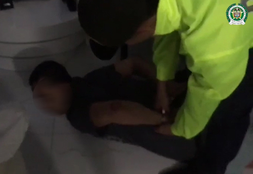 Policía está esposando a un hombre capturado en Medellín