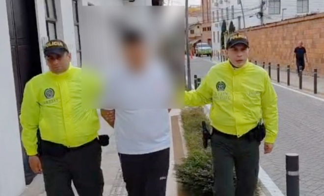 Hombre capturado viste de camiseta blanca en medio de dos polic&iacute;as