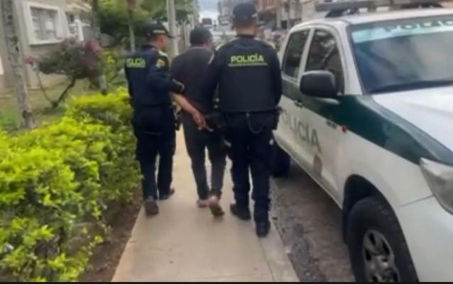Hombre capturado en medio de dos Policías caminando hacía una patrulla de Policía