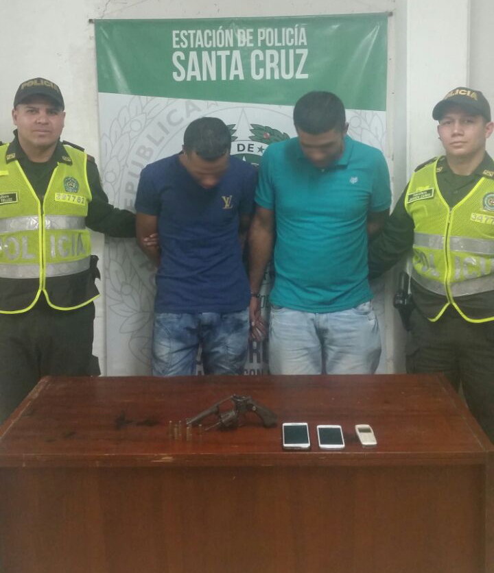 Dos hombres con esposas son sujetados por dos policías