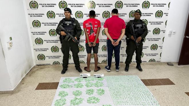 Dos hombres de camiseta roja capturados en medio de dos polic&iacute;as