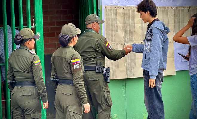 Tres policía realizan control al ingreso de una institucional educativa asignada como puesto de votación