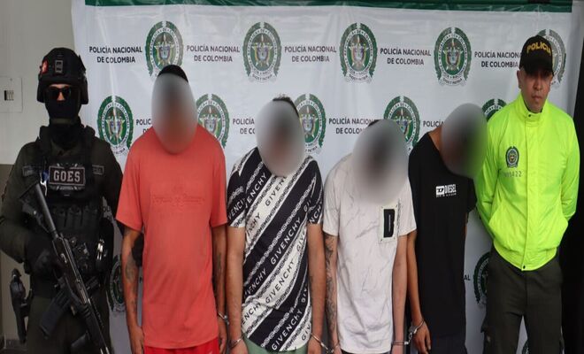 Cuatro personas detenidas son presentadas por dos uniformados de la Polic&iacute;a Nacional de Colombia