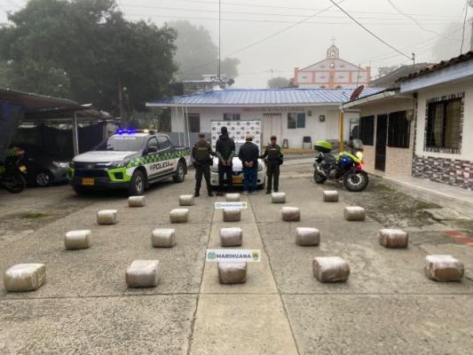Dos polic&iacute;as, al lado de dos hombres capturados con marihuana y un veh&iacute;culo incautados