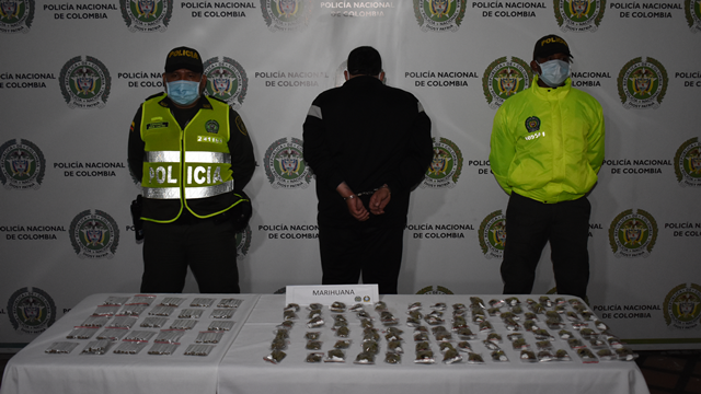 una persona capturada-policías custodiando-alucinógenos sobre una mesa