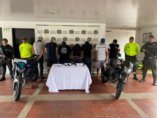 Personas capturadas-policías custodiando