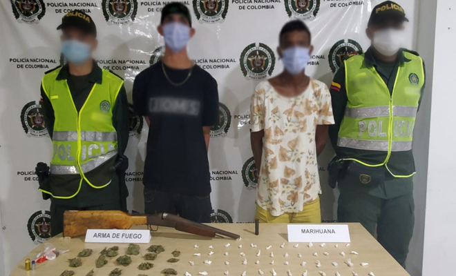 Dos personas capturadas-policías custodiando-arma de fuego incautada- alucinógenos incautados