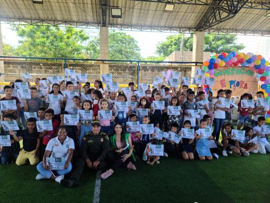Niños y niñas mostrando el diploma de graduación