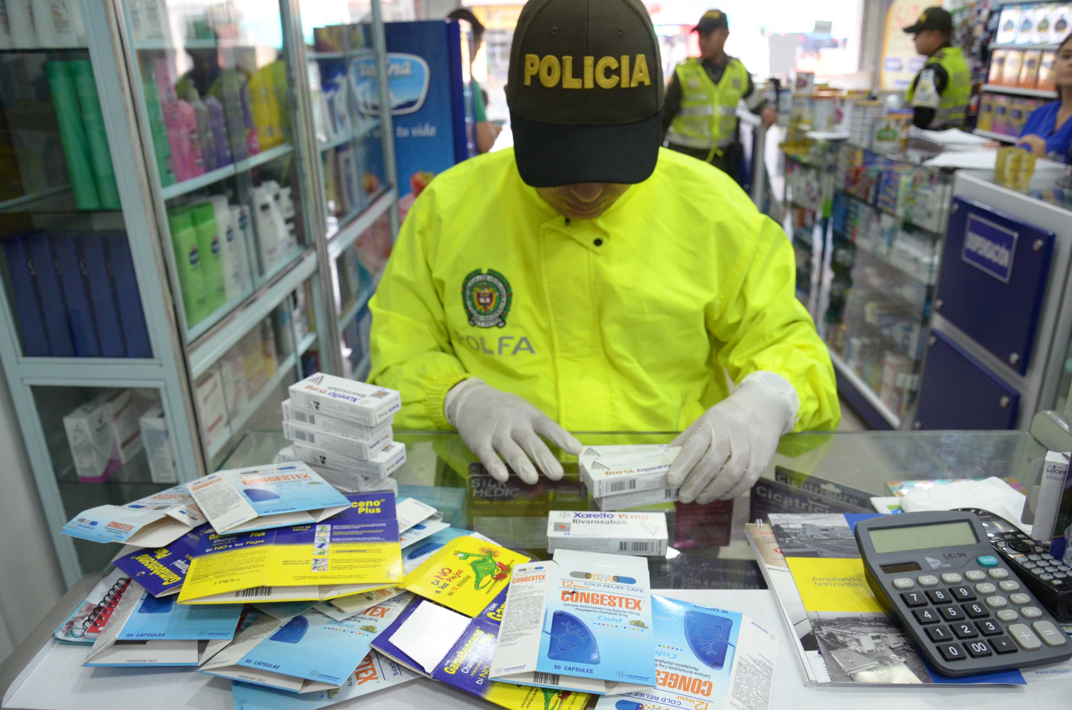 Policía revisa cajas con medicamentos sobre una vitrina